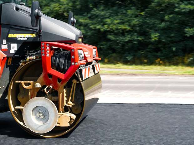 Rolo compactador em via de acesso recém-asfaltada